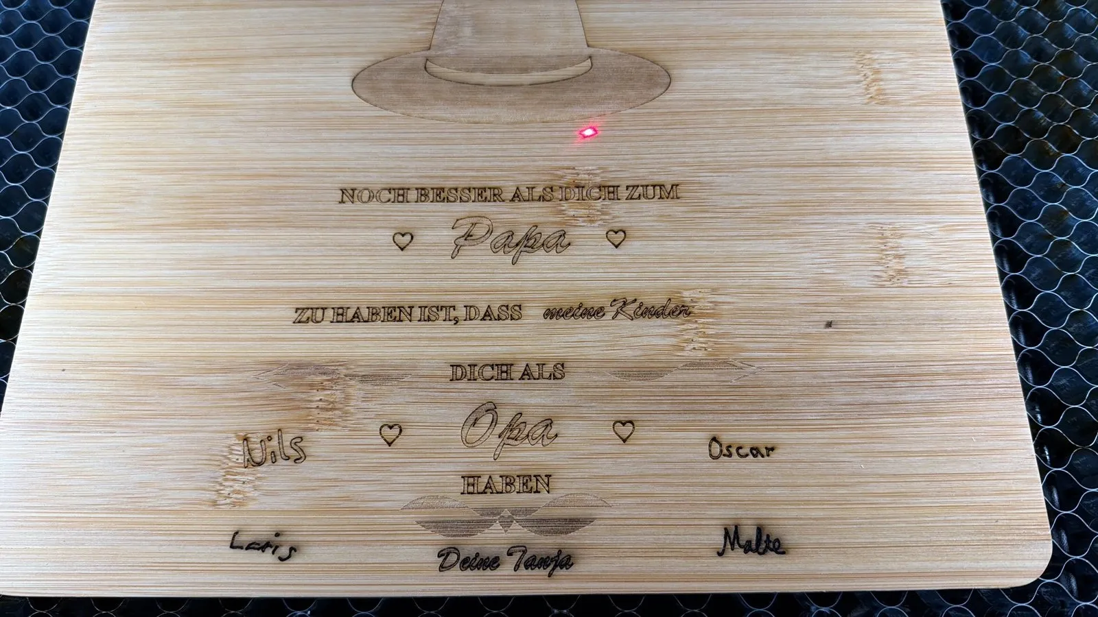 Schneidebrett mit gravierten Kindernamen in Handschrift, im Laser liegend